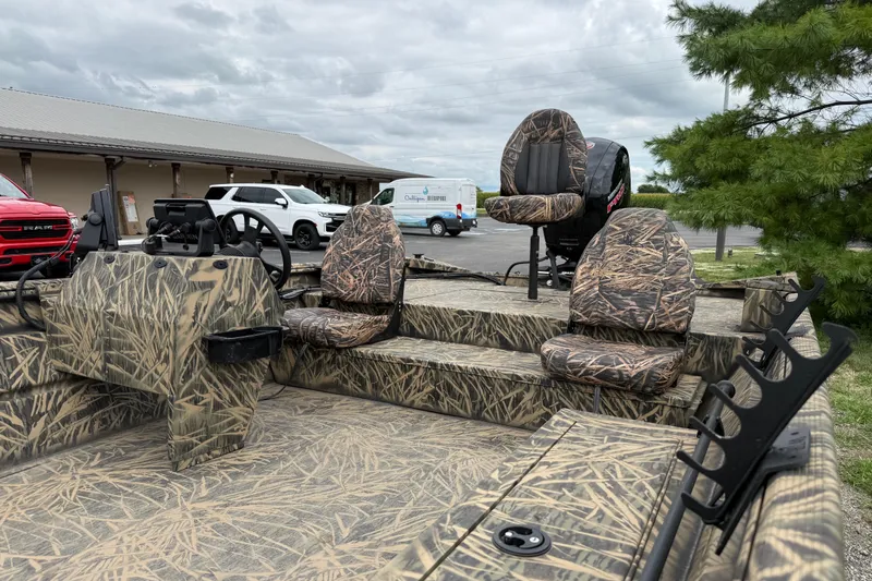 Slide: The Image of 2023 Lowe Roughneck 2070SC boat with camouflage seats and steering, parked outdoors. - 10