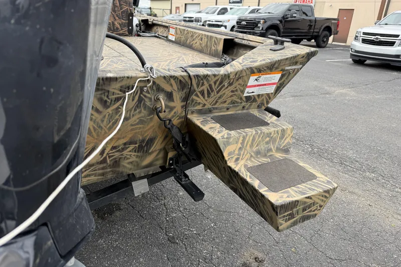 Slide: The Image of 2023 Lowe Roughneck 2070SC boat with camouflage design and rear steps in a parking lot. - 19