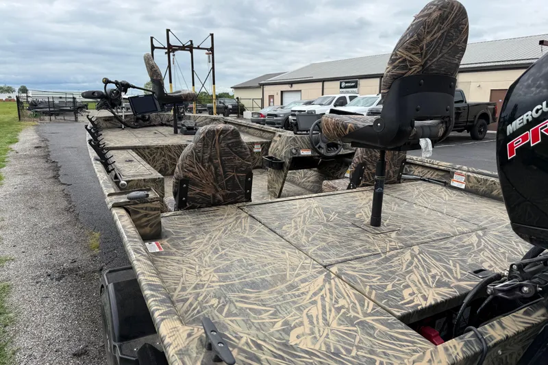 Slide: The Image of 2023 Lowe Roughneck 2070SC boat with camouflage seats and Mercury engine, parked outdoors. - 20