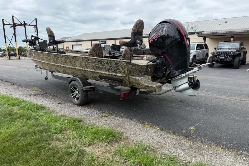 Slide: The Image of 2023 Lowe Roughneck 2070SC boat on trailer, parked outdoors near vehicles. - 5