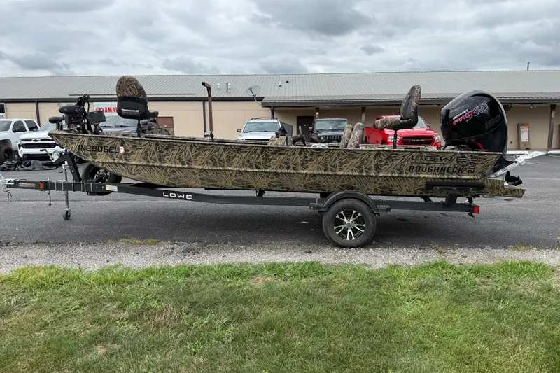 Slide: The Image of 2023 Lowe Roughneck 2070SC boat on trailer, camo design, parked outdoors. - 6