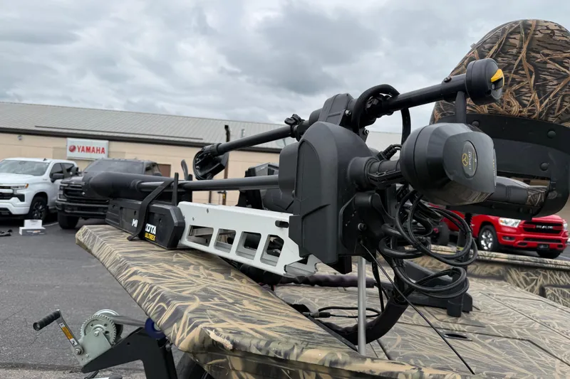 Slide: The Image of 2023 Lowe Roughneck 2070SC boat with camo design and trolling motor, parked near vehicles. - 8