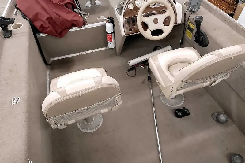 Slide: The Image of Interior of a 2005 Monark Signature 1601 boat with beige seats and steering console. - 13