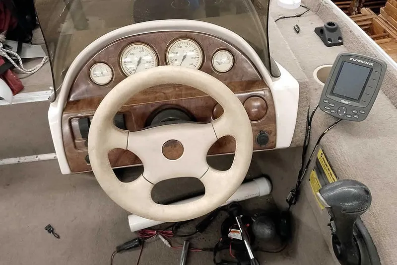 Slide: The Image of 2005 Monark Signature 1601 boat dashboard with steering wheel and Lowrance fish finder. - 14