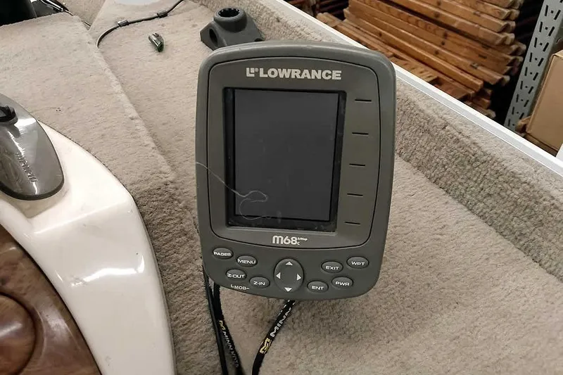 Slide: The Image of Lowrance M68c fishfinder on 2005 Monark Signature 1601 boat, carpeted surface, wooden planks background. - 15
