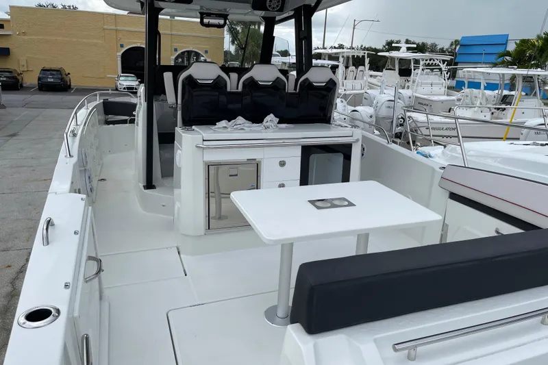 Slide: The Image of 2024 Jeanneau Leader 10.5 CC boat interior with seating and table, docked at marina. - 5