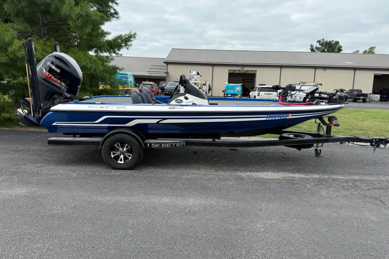 Slide: The Image of 2018 SKEER ZX190 boat on trailer, parked outdoors near a building. - 2