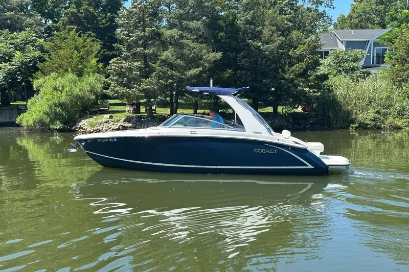 Slide: The Image of 2016 Cobalt R5 boat cruising on a calm river, surrounded by lush greenery. - 2
