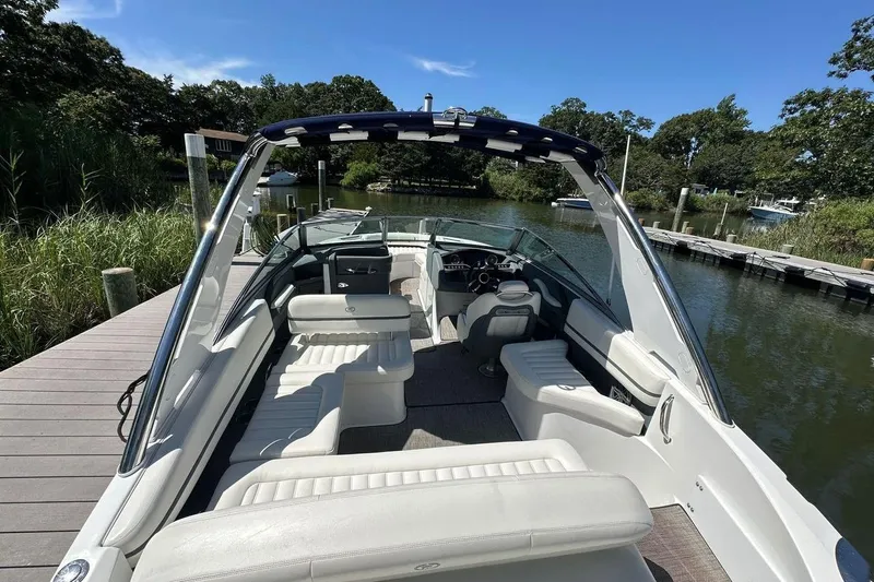 Slide: The Image of 2016 Cobalt R5 boat with white seating, docked in a scenic, tree-lined marina. - 6