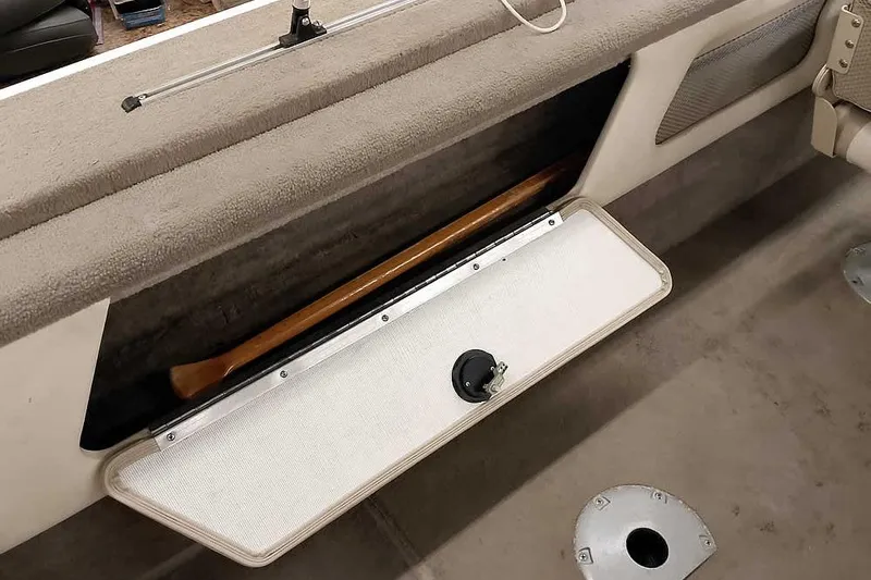 Slide: The Image of Storage compartment in a 2005 Monark King 185 boat, featuring a wooden paddle. - 30