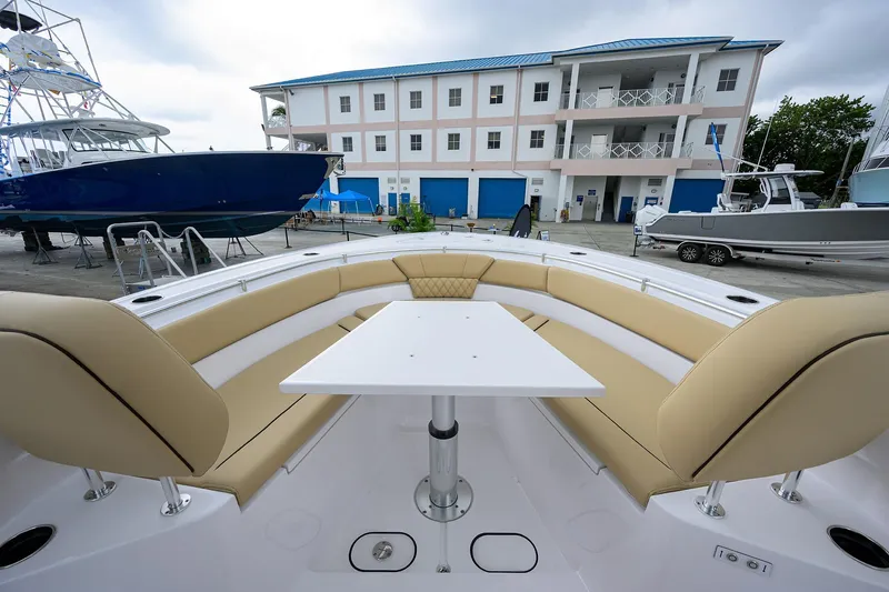 Slide: The Image of 2026 Sportsman Heritage 261 Center Console with beige seating and table, docked near a marina. - 19