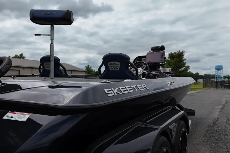 Slide: The Image of 2021 Skeeter FXR21 Apex boat with advanced navigation equipment, parked outdoors under cloudy skies. - 18