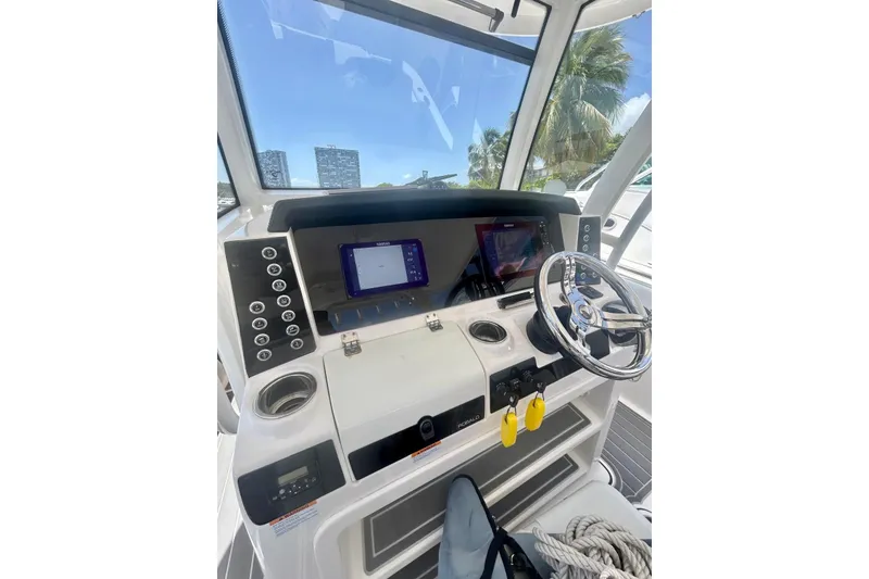 Slide: The Image of 2021 Robalo R302 Center Console boat dashboard with steering wheel and navigation screens. - 13