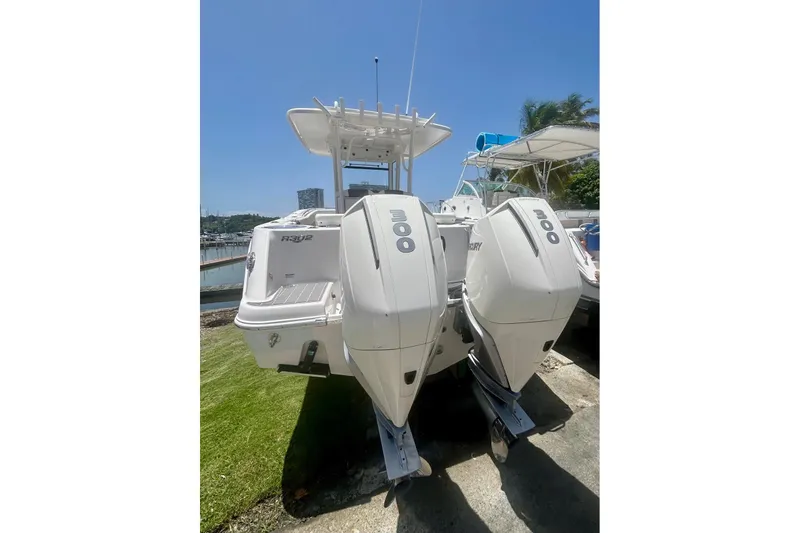 Slide: The Image of 2021 Robalo R302 Center Console boat with twin outboard engines, docked under clear blue sky. - 8