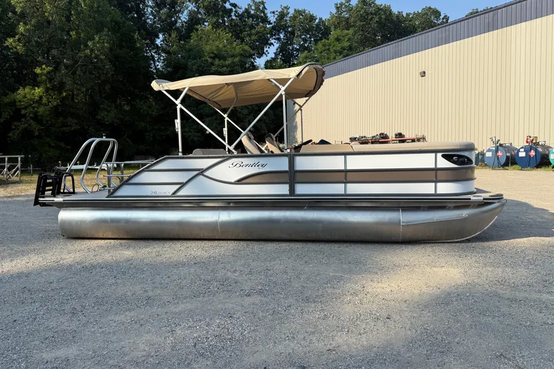 Slide: The Image of 2026 Bentley Pontoons Legacy 243 Swingback EXT with canopy, parked outdoors. - 2