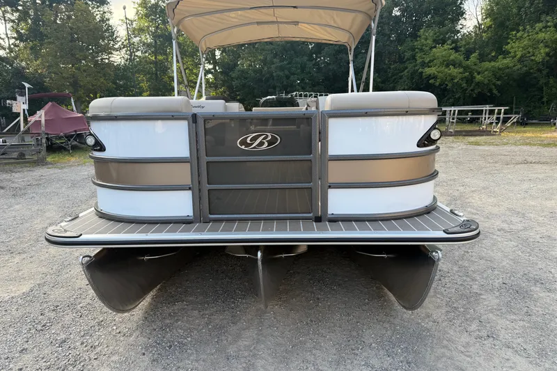 Slide: The Image of 2026 Bentley Pontoons Legacy 243 Swingback EXT, front view, parked on gravel, with canopy. - 4