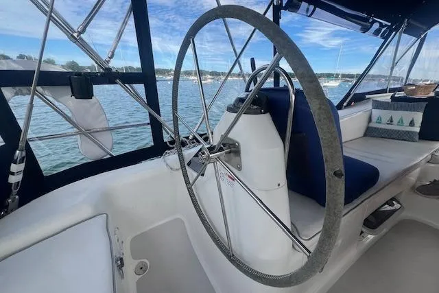 Slide: The Image of 2003 Catalina 470 Sloop cockpit with steering wheel, overlooking serene waters. - 17
