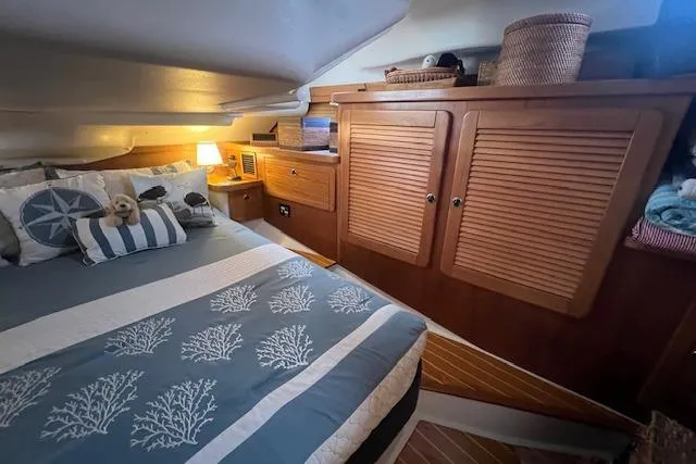 Slide: The Image of Cozy cabin interior of 2003 Catalina 470 Sloop with wing keel, featuring wooden cabinets and nautical bedding. - 33