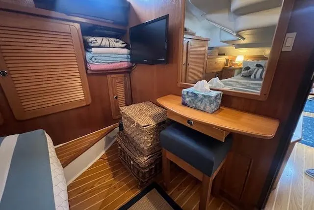 Slide: The Image of Cozy interior of 2003 Catalina 470 Sloop, featuring wooden cabinetry and a small desk area. - 34
