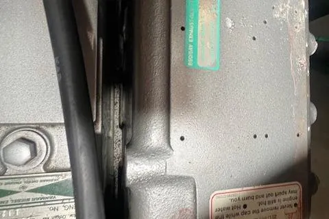 Slide: The Image of Close-up of a 2003 Catalina 470 Sloop engine component with visible labels and cables. - 38