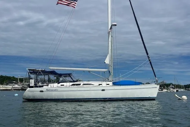 Slide: The Image of 2003 Catalina 470 Sloop with wing keel, anchored under cloudy sky, American flag flying. - 45