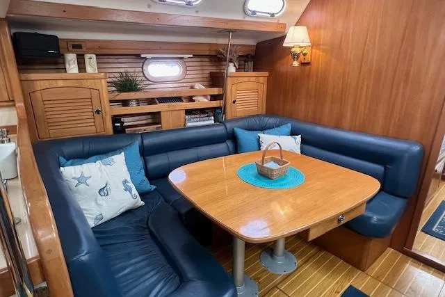 Slide: The Image of Interior of 2003 Catalina 470 Sloop, featuring a cozy dining area with blue seating. - 5