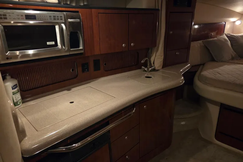 Slide: The Image of 2007 Sea Ray 320 Sundancer interior with kitchenette and bed, featuring wood cabinetry and modern appliances. - 14