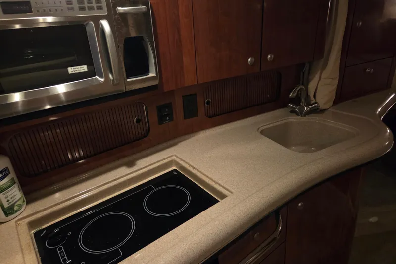 Slide: The Image of 2007 Sea Ray 320 Sundancer kitchen with microwave, stove, sink, and wooden cabinetry. - 15