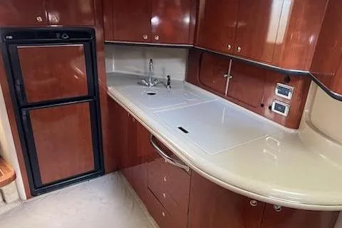 Slide: The Image of 2003 Sea Ray Sundancer 460 yacht kitchen with wood cabinets and compact fridge. - 35