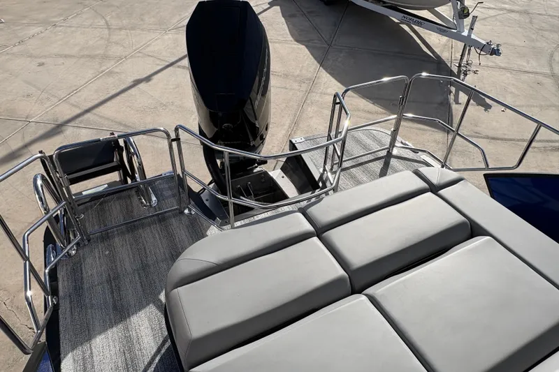 Slide: The Image of 2026 Bennington 26 MCSB boat with cushioned seating and outboard motor, docked on concrete. - 14