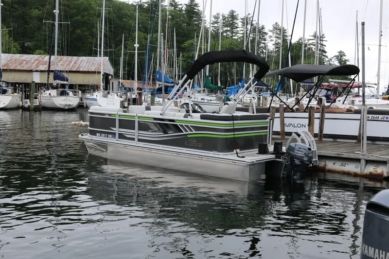 Slide: The Image of 2025 SunCatcher Select 18C pontoon boat docked at marina with sailboats. - 1