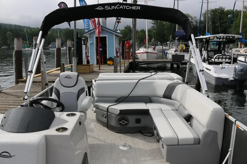 Slide: The Image of 2025 SunCatcher Select 18C pontoon boat docked at a marina with seating area. - 3