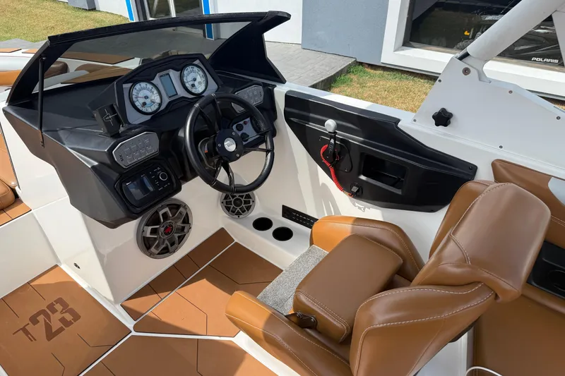 Slide: The Image of 2021 Axis T23 boat interior with brown seats, steering wheel, and dashboard controls. - 13