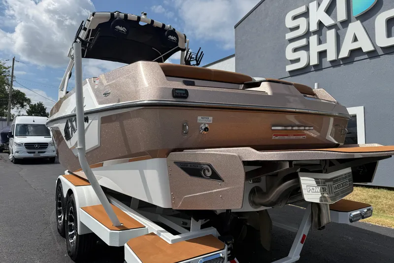 Slide: The Image of 2021 Axis T23 boat on trailer outside Ski Shack, under a partly cloudy sky. - 7