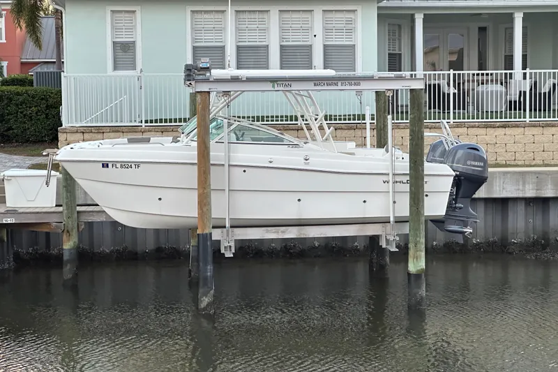 Slide: The Image of 2021 World Cat 230 SD boat on lift by waterfront home, featuring Yamaha outboard motor. - 117