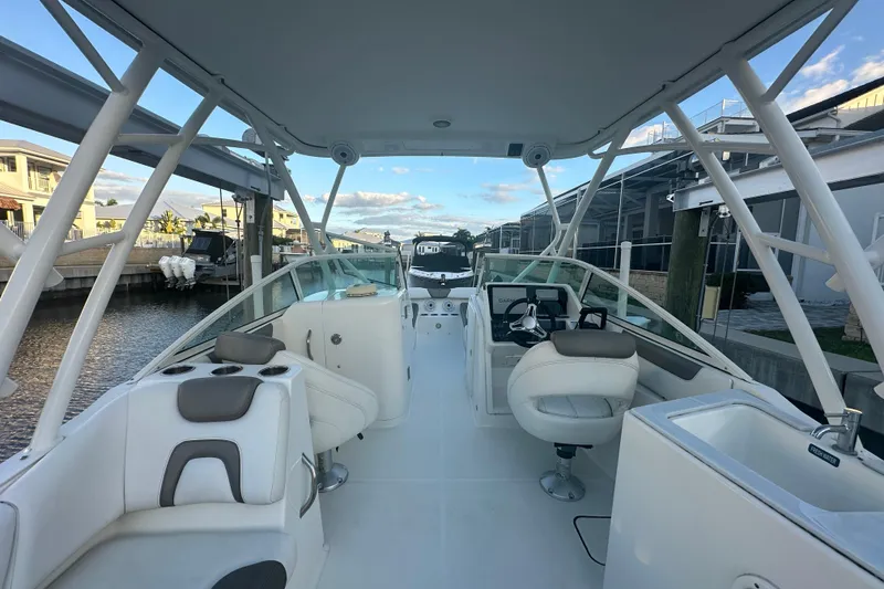 Slide: The Image of 2021 World Cat 230 SD boat interior with seating and helm, docked by waterfront homes. - 13