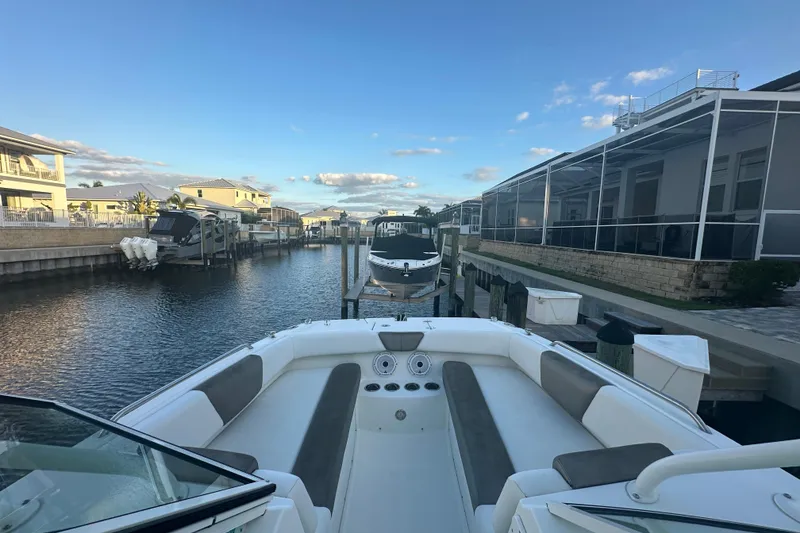 Slide: The Image of 2021 World Cat 230 SD boat docked in a residential canal under a clear blue sky. - 29
