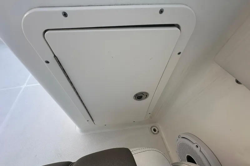 Slide: The Image of Storage compartment on 2021 World Cat 230 SD boat interior, featuring a secure latch and speaker. - 77