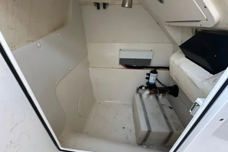 Slide: The Image of 2021 World Cat 230 SD boat interior storage compartment with equipment and wiring. - 99