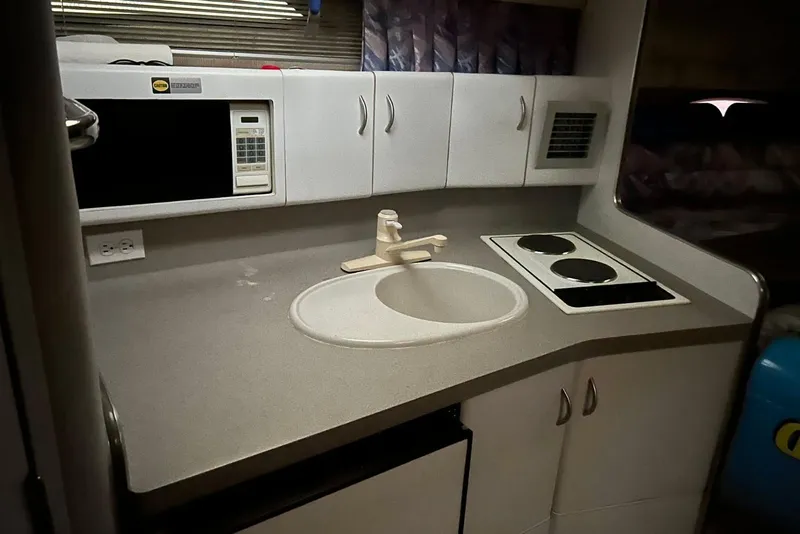 Slide: The Image of 1991 Four Winns 325 Express Vista boat kitchen with sink, stove, and microwave. - 10