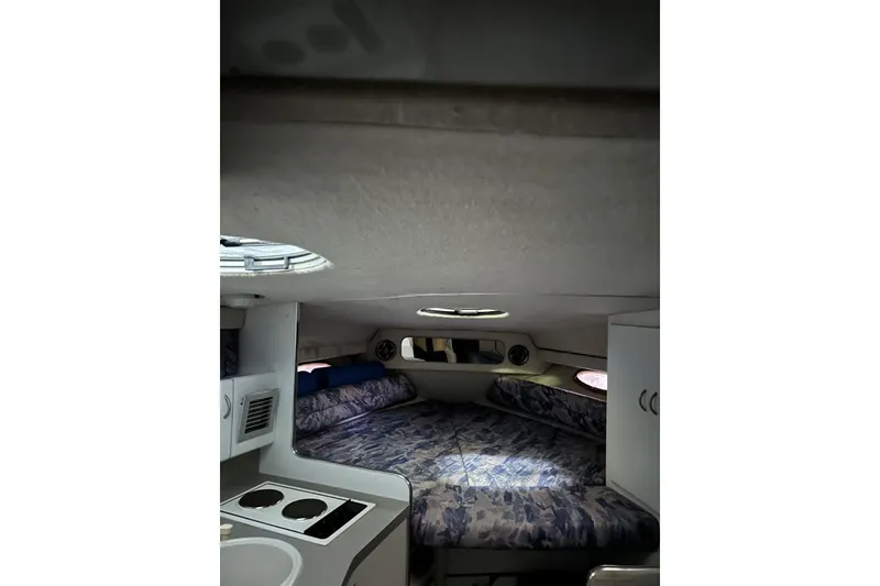 Slide: The Image of Interior cabin of 1991 Four Winns 325 Express Vista boat, featuring a cozy bed and kitchenette. - 12