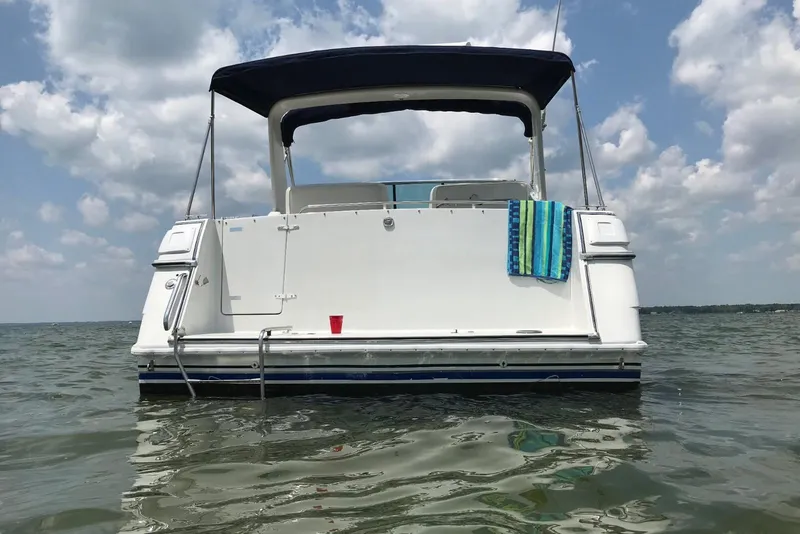 Slide: The Image of 1991 Four Winns 325 Express Vista boat on water, with towel and cup, under blue sky. - 13