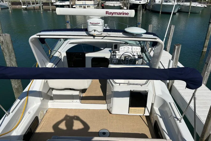 Slide: The Image of 1991 Four Winns 325 Express Vista boat docked, featuring Raymarine equipment and spacious cockpit. - 6
