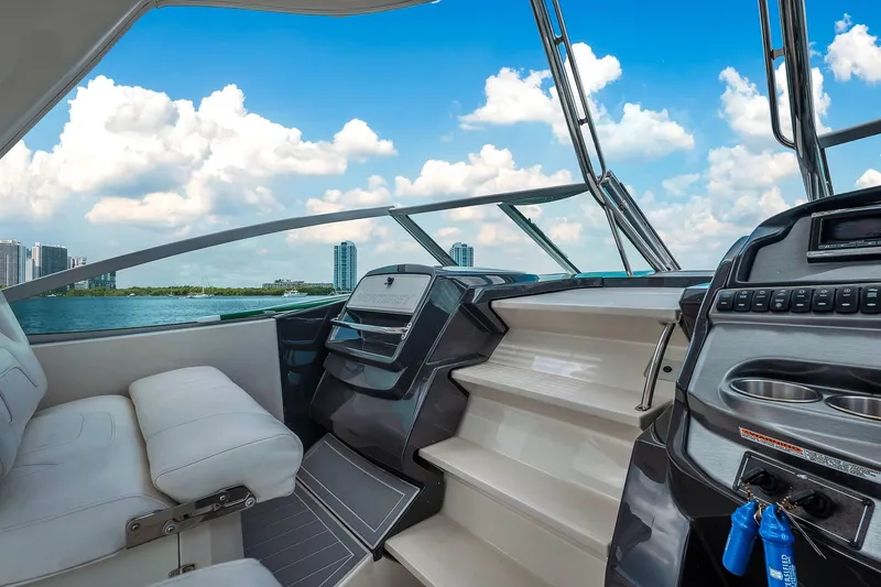Slide: The Image of 2014 Monterey 320 Sport Yacht interior with luxurious seating and modern dashboard, under a clear blue sky. - 24