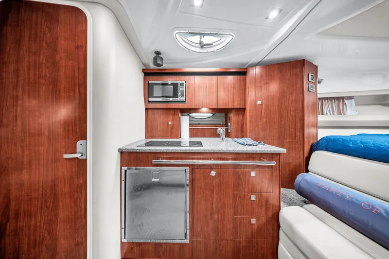 Slide: The Image of Interior of 2014 Monterey 320 Sport Yacht with modern kitchenette and wood cabinetry. - 34