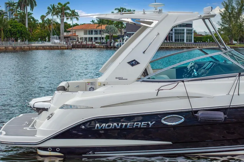 Slide: The Image of 2014 Monterey 320 Sport Yacht docked by waterfront homes, showcasing sleek design and luxury features. - 6