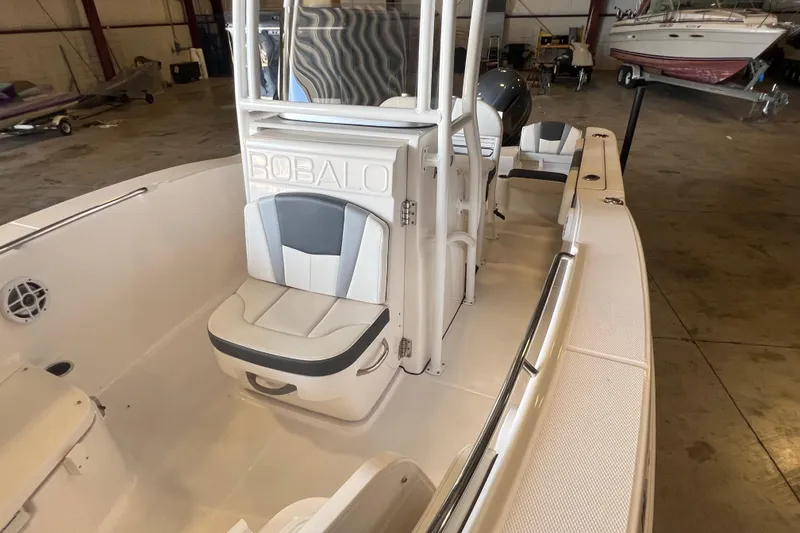 Slide: The Image of 2023 Robalo R200 Center Console boat interior with seating and storage in a warehouse setting. - 14