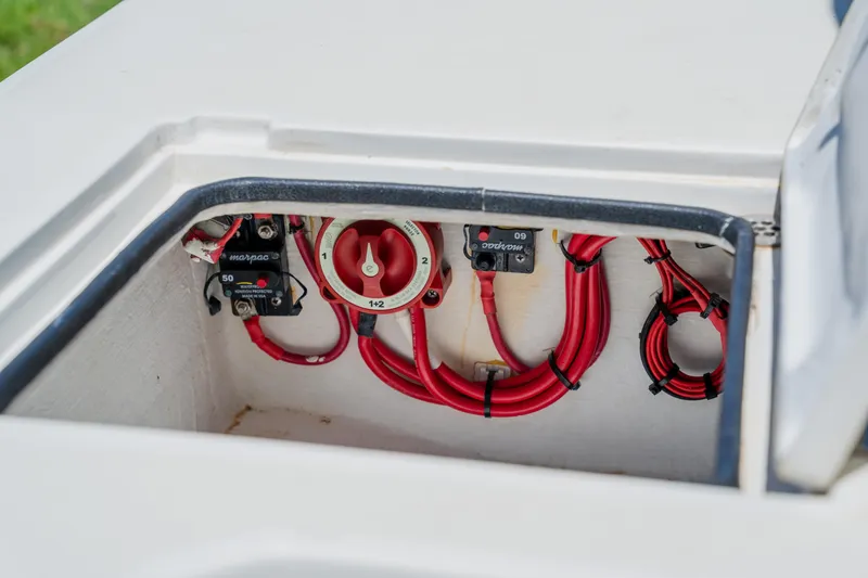 Slide: The Image of 2008 Lake & Bay Boca Grande 20 boat battery compartment with red cables and switches. - 70