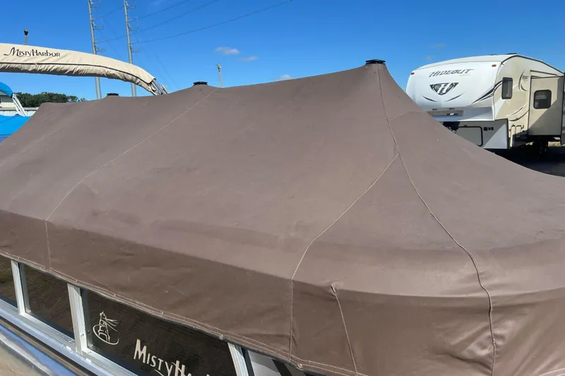 Slide: The Image of 2014 Misty Harbor 2285 Biscayne Bay CU pontoon boat with brown cover, parked near RV. - 39