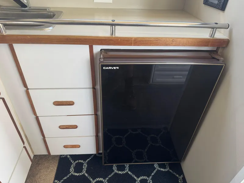 Slide: The Image of 1986 Carver Mariner 28 interior with compact fridge and wooden cabinetry. - 7
